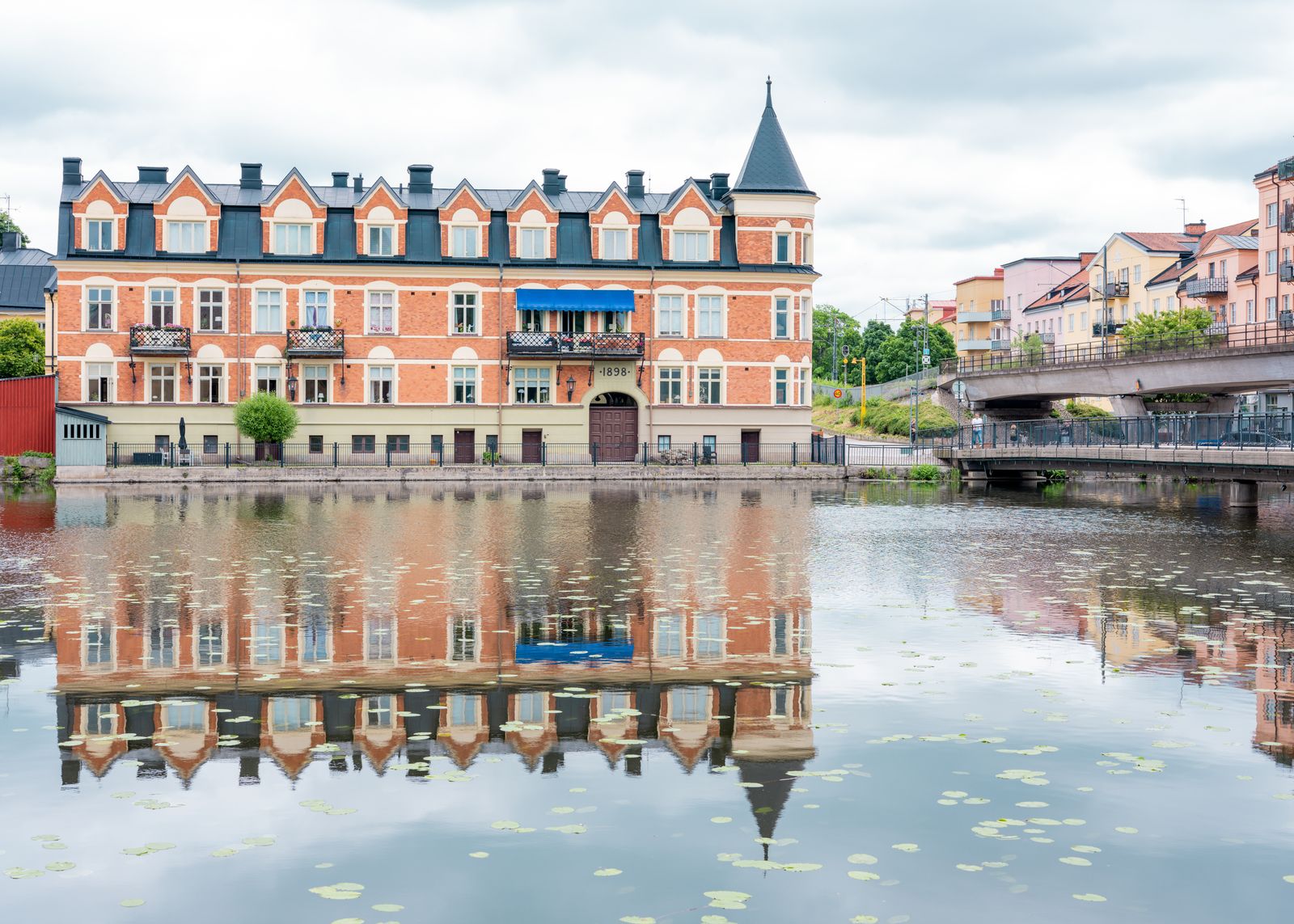 Stenhus vid Eskilstunaån som speglas i vattnet en sommardag